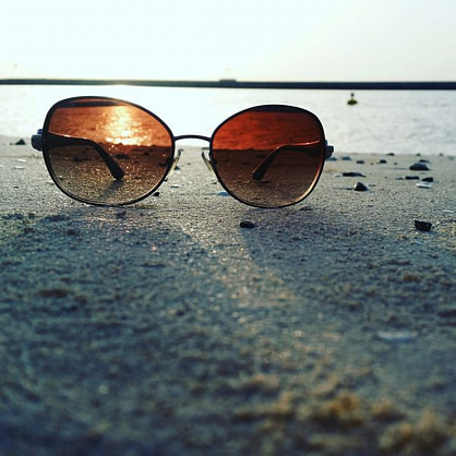 gold_framed_aviator_style_sunglasses_on_gray_sand-scopio-ec27fae1-729d-4673-b471-7df8ea2d0202-min glasses focused on sunset