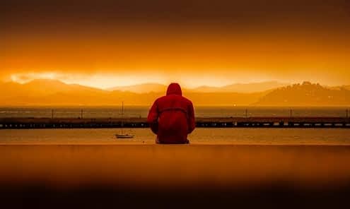 person-wearing-red-hoodie-sitting-in-front-of-body-of-water-636164-min hypnosis depression guy in front of sea